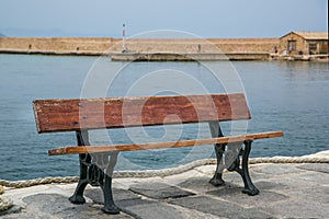 Young woman sitting on the bench and looking at old port in Chania, Greece