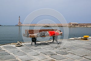 Young woman sitting on the bench and looking at old port in Chania, Greece