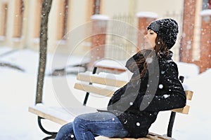 Young woman sitting on the bench in park and looking away