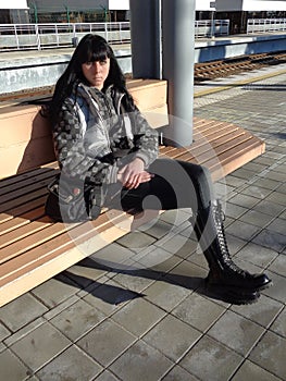 Young woman sitting on bench at railway platform