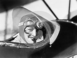 Young woman sitting in a biplane with hat and gargles