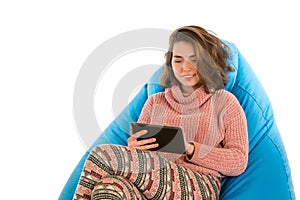 Young woman sitting on blue beanbag chair and holding a tablet i