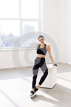 Young woman sitting on a box at gym after her workout. Female athlete taking rest after exercising at gym