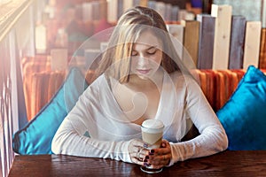 Young woman sitting in cafe with cup of coffe