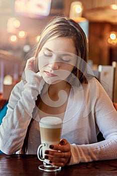 Young woman sitting in cafe with cup of coffe