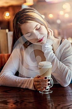 Young woman sitting in cafe with cup of coffe