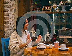 Young woman sitting in cafeteria and talking with sign language.