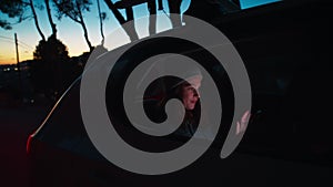 Young woman sitting in car at night using phone