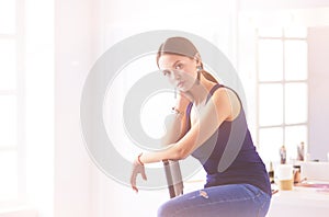 Young woman sitting on a chair isolated over white background