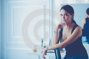 Young woman sitting on a chair isolated over white background