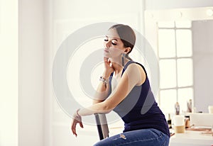 Young woman sitting on a chair isolated over white background