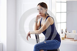 Young woman sitting on a chair isolated over white background