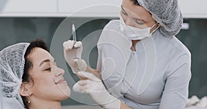 Young woman sitting in chair while visiting a beautiful female cosmetologist. Preparation for cosmetic procedures. Lip