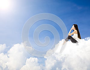 Young woman sitting on cloud and dreaming