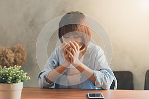 Young woman sitting in coffee shop at wooden table, drinking coffee and using smartphone.