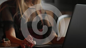 Young woman sitting in coffee shop at wooden table, drinking coffee and using smartphone.On table is laptop. Girl