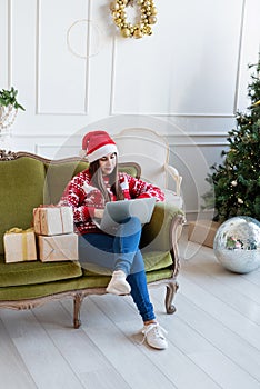 Young woman sitting on couch in a decorated living room working on laptop computer