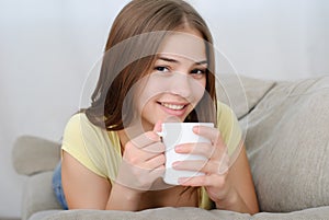 Young woman sitting on couch and drinking coffee