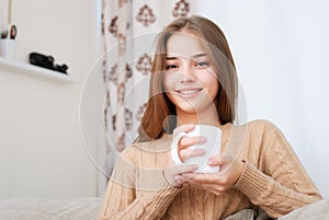 Young woman sitting on couch and drinking coffee