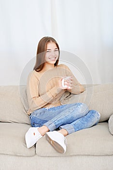 Young woman sitting on couch and drinking coffee