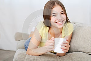 Young woman sitting on couch and drinking coffee