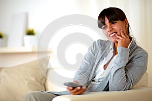 Young woman sitting on couch with tv remote