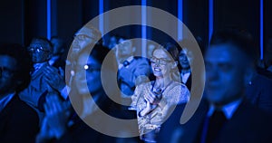 Young Woman Sitting in a Crowded Audience at a Business Conference. Female Attendee Cheering and