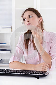 Young woman sitting at desk having pains in the neck or swollen