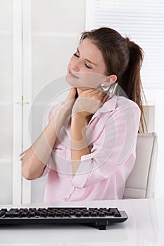 Young woman sitting at desk having pains in the neck or swollen photo