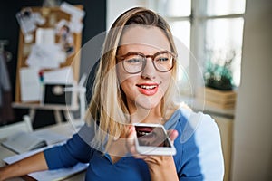 Young woman sitting at the desk indoors in home office, working.