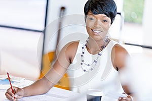 Young woman sitting at a desk in an office and working on blueprint