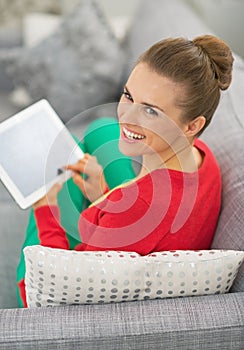 Young woman sitting on divan and using tablet pc