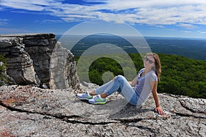 Young woman sitting at the edge of roc at Minnewaska State Park