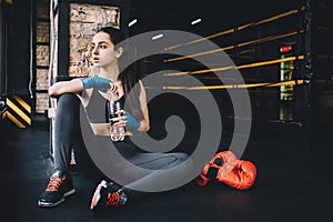 Young woman sitting on the floor after hard workout in gym.