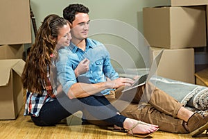 Young woman sitting on floor and using laptop