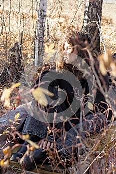 Young woman sitting in forest with eyes closed and peaceful smile