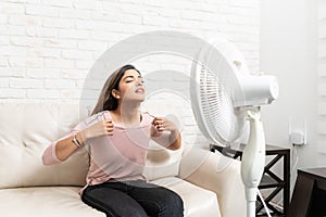 Young Woman Sitting In Front Of Fan At Home