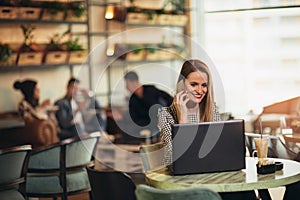 Young woman sitting in front of open laptop computer in cafe bar