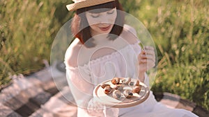 young woman sitting on the grass and holding wooden plates with tasty french food