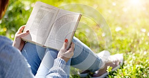 Young woman sitting on the grass and reading a book.