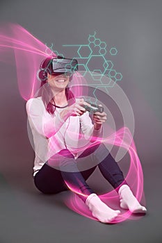 Young woman sitting and having fun playing a virtual reality video game against a dark background