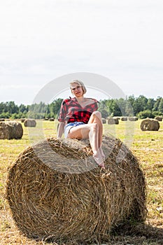 Young woman sitting on hay bale