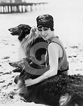 Young woman sitting with her Collies on the beach photo