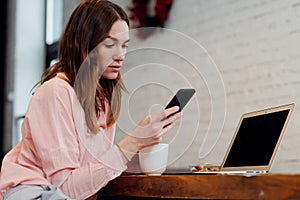 Young woman sitting at her desk with a smartphone