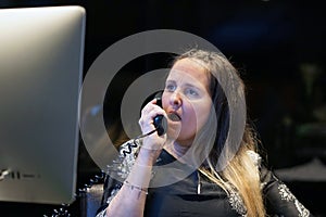 Young woman sitting at her desk working and answering a phone call.