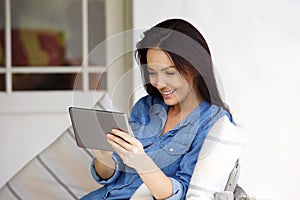 Young woman sitting at home using digital tablet