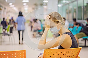 Young woman sitting in hospital waiting for a doctor`s appointment. Patients In Doctors Waiting Room