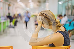 Young woman sitting in hospital waiting for a doctor`s appointment. Patients In Doctors Waiting Room