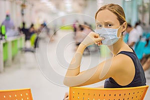 Young woman sitting in hospital waiting for a doctor`s appointment. Patients In Doctors Waiting Room