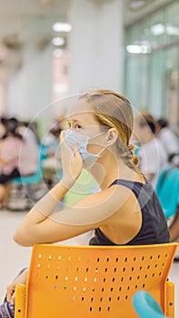 Young woman sitting in hospital waiting for a doctor`s appointment. Patients In Doctors Waiting Room VERTICAL FORMAT for